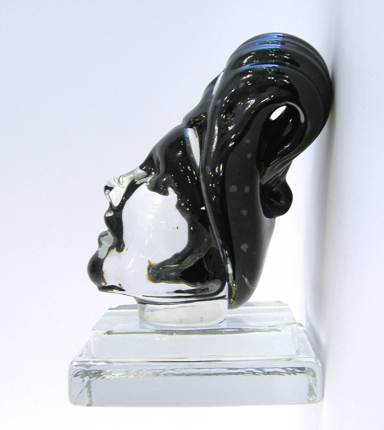 1980s blown Murano glass sculpture of a head with unique black glass hairdo with handcrafted features, on a stepped clear glass base. One-of-a-kind work of art with versatile use, as a decorative accent or paperweight.