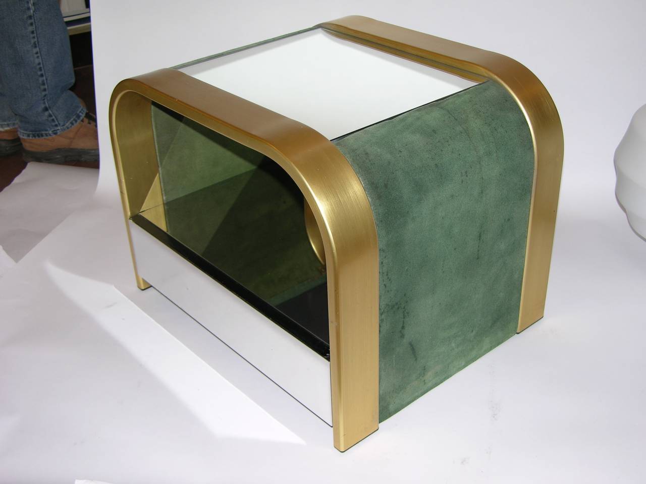 Unusual pair of open side tables by Romeo Rega, the rare curved design is accented with sophisticated use of different finishes: one drawer with chromed front under a mirrored shelf in the brass edged structure highlighted with a mirrored top and