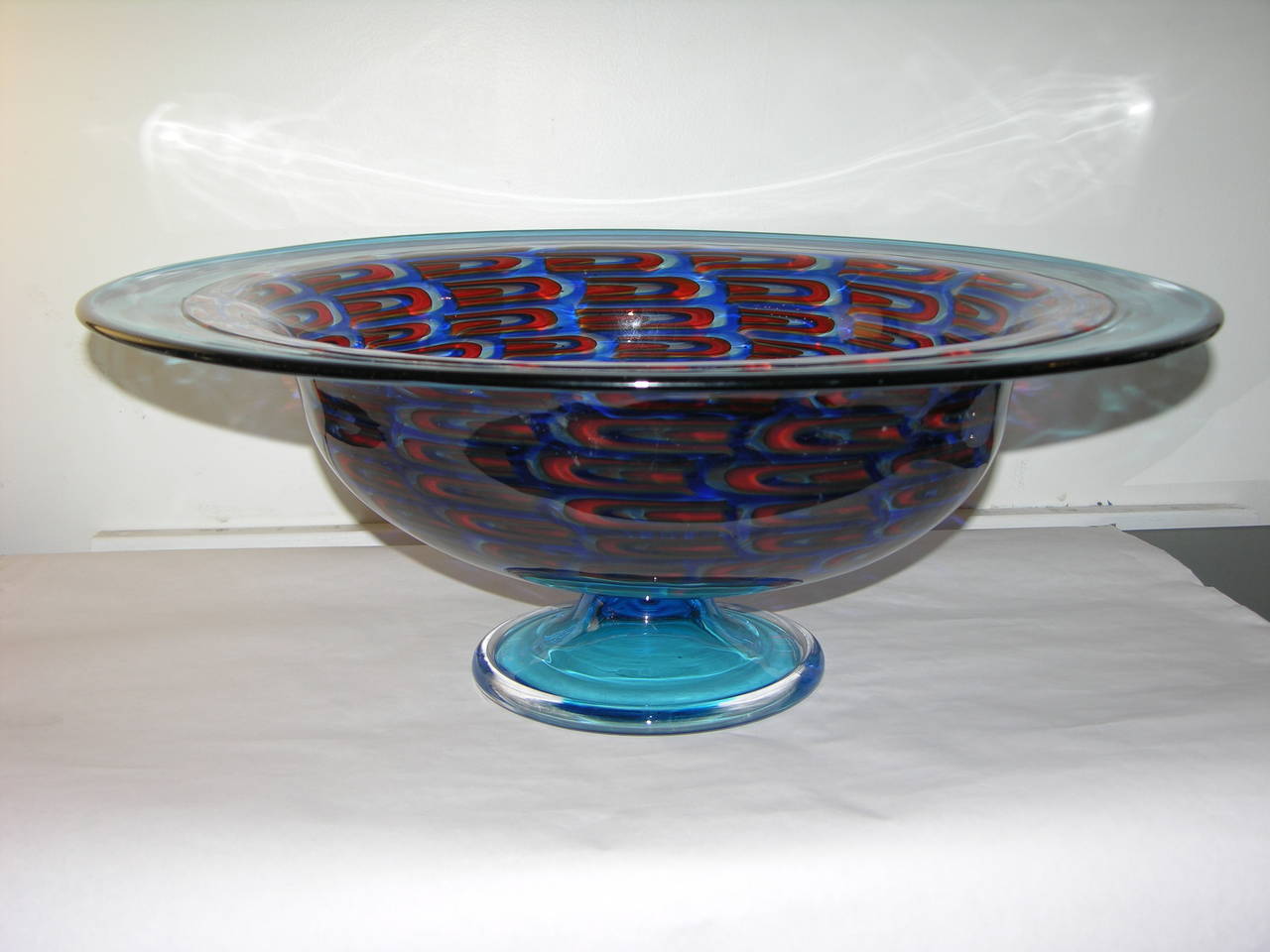 A collector piece, superb and precious work of art, this grand center bowl in mouth blown Murano glass is decorated with Murrine in crimson and turquoise, with a wide turquoise border worked 