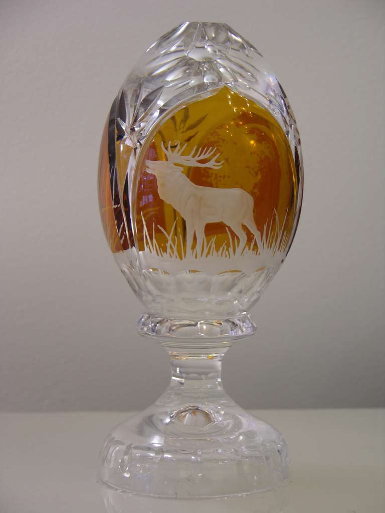 1970s egg-shaped Bohemian overlaid blown glass, all hand engraved with gothic design decorated with an engraved animal, very high quality hand cuts all around also on the base. The amber color is pure gold in the glass. 
This piece engraved with a