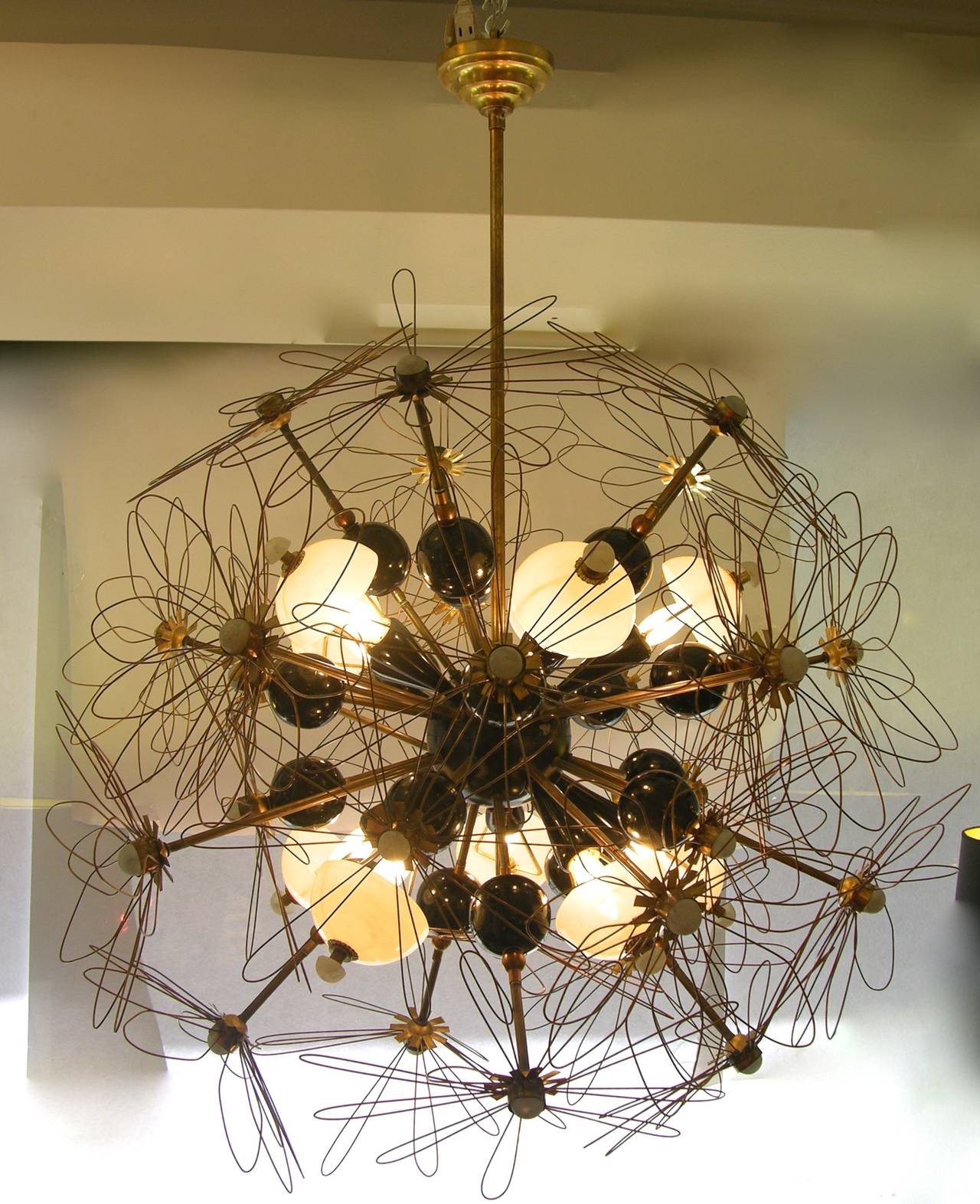 1960s unique Italian organic and very fun chandelier, entirely handcrafted, bronze rods decorated with brass flower silhouettes and black painted metal spheres jutting out of a central black metal core supporting ten conical black sockets with bulbs