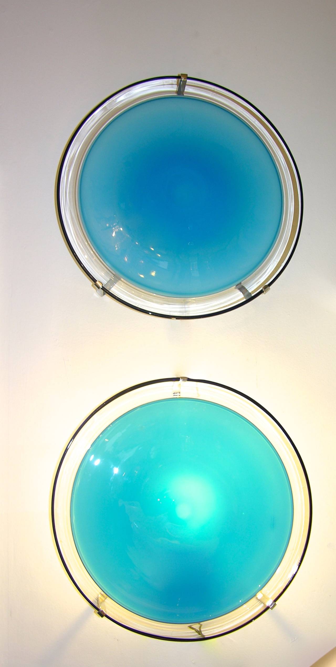 Chic pair of Italian wall or ceiling lights by Leucos. The round disks, in mouth blown glass of aqua blue color and elegantly worked with a clear border 