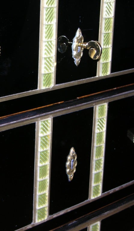 A very elegant Italian dresser with 3 drawers, whole covered in black opaline mirrored glass and edged in bronze, the drawers and the bronze handles decorated with mosaic of gold and pale green glass. Each bronze edged leg, front and back, is