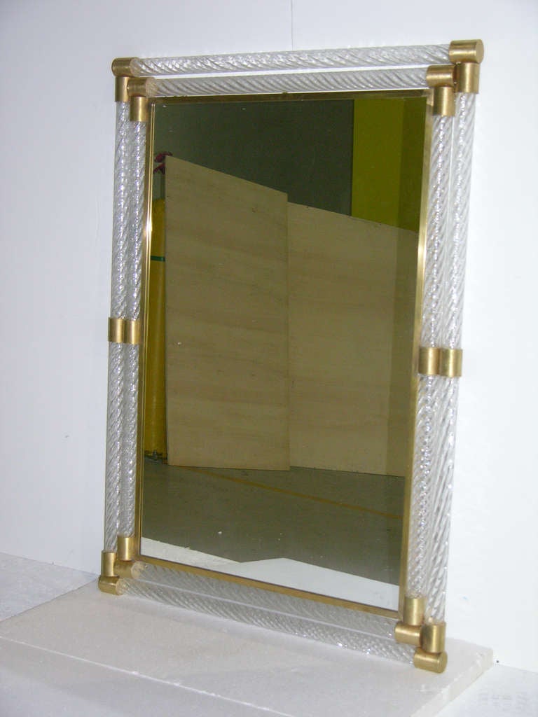 1960s Italian mirror attributed to Barovier-Toso, the central plate edged in bronze and surrounded by twisted clear Murano glass pipes encased in handcrafted gilded bronze corners, with bronze accents on the sides. 
Can be hung horizontally or