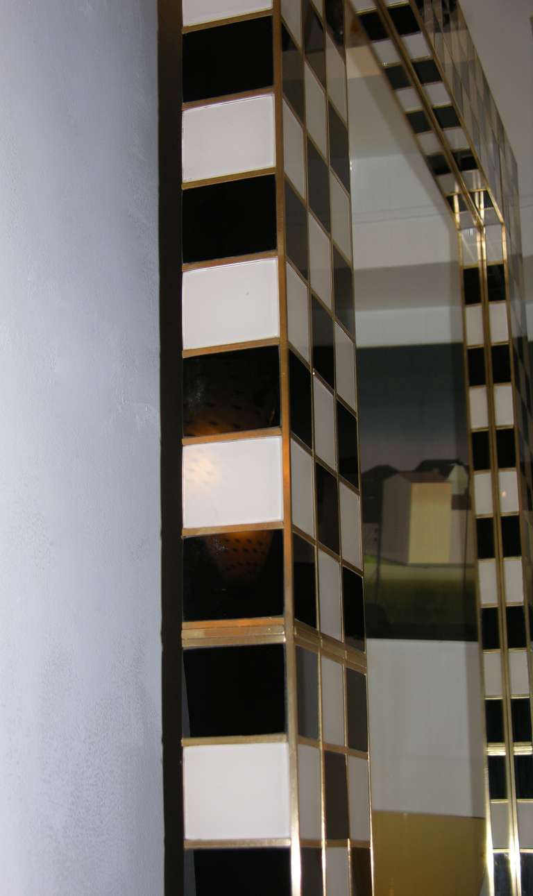 Whole handmade Italian mirror from the 1970s, a work of art for the extraordinary execution and incredible craftsmanship: each small squared tile in white or in black Murano glass is individually outlined with a bronze edge, the checkered design in