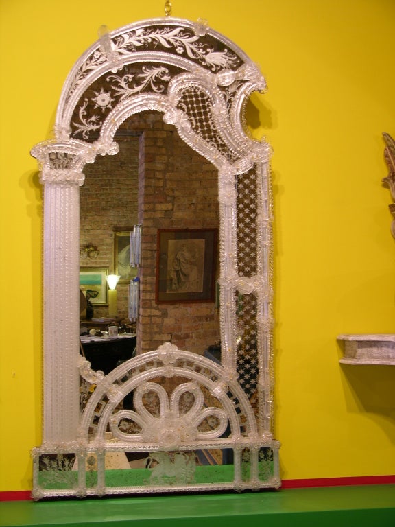 Exquisite Venetian mirror in Murano glass whole hand made, the arched-shape design with a side column consisting of many mouth blown twisted rods is unique, the surround finely decorated with Murano glass borders in relief embellished with glass