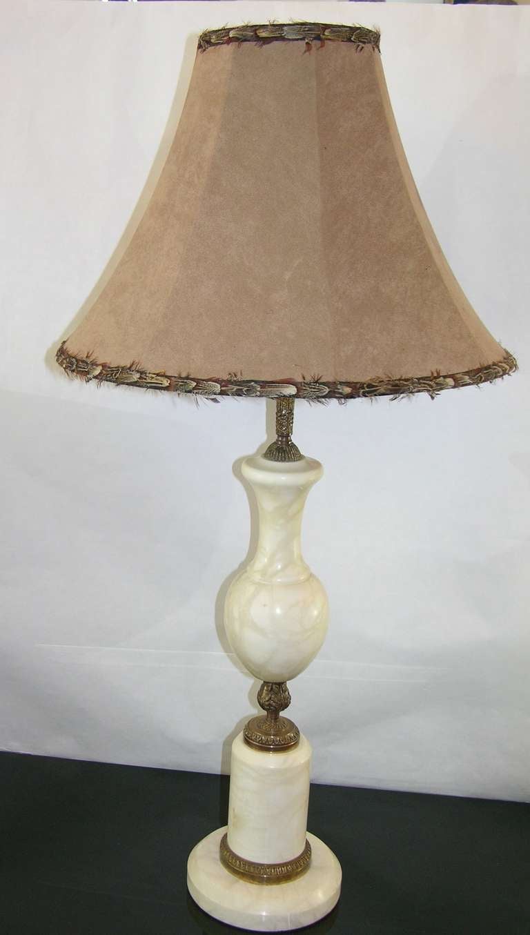 A 1920s Art Deco French rustic lamp, the nicely turned white marble decorated with bronze chasing with leaf motif, with a later suede feather-edged shade. 
Measure: The base has a diameter of 6.25 inches.