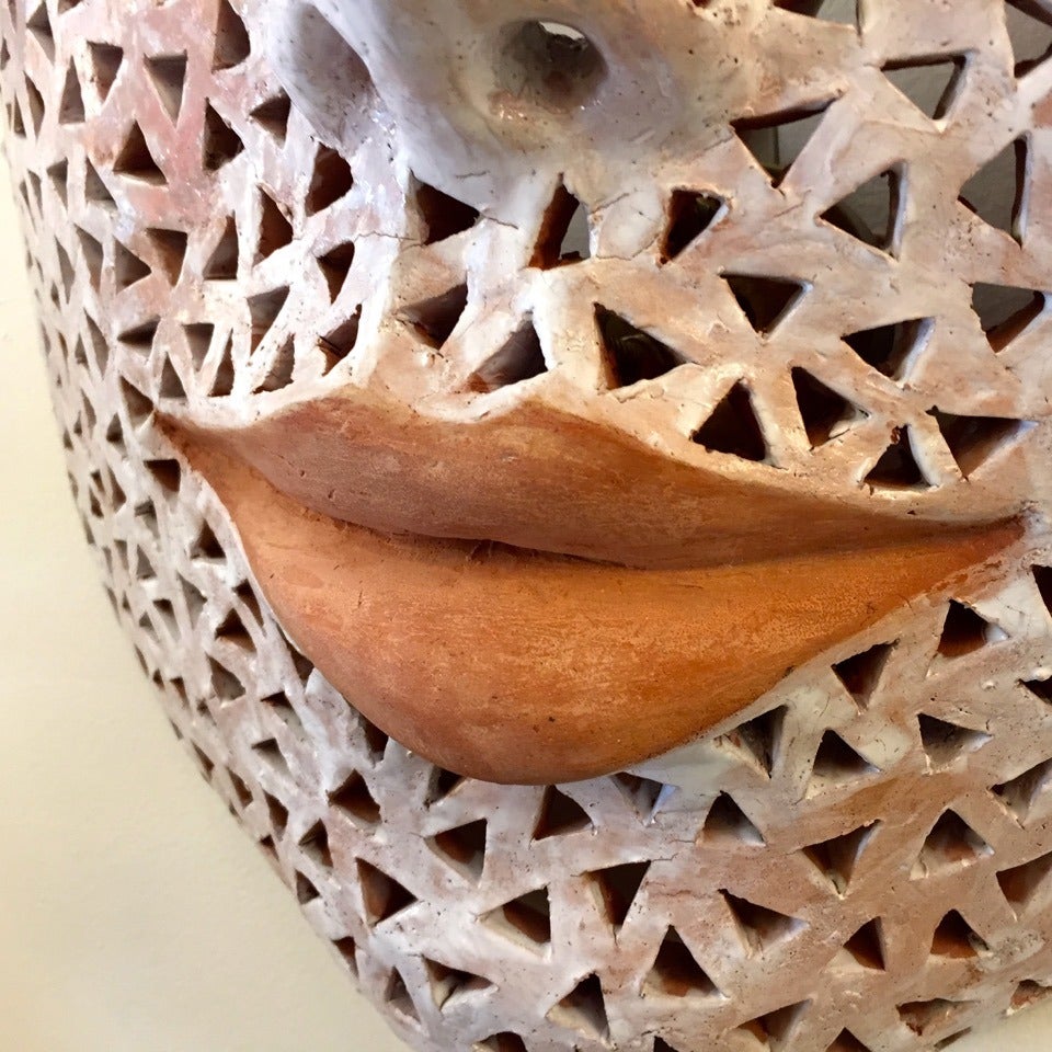 Zeitgenössische Skulptur aus Terrakotta in Form einer weiblichen Maske, handgefertigt mit einer durchbrochenen Verzierung und weißem Pinsel, der mit gebranntem Email bemalt ist. Diese Wanddekoration hat eine besondere Einzigartigkeit durch die