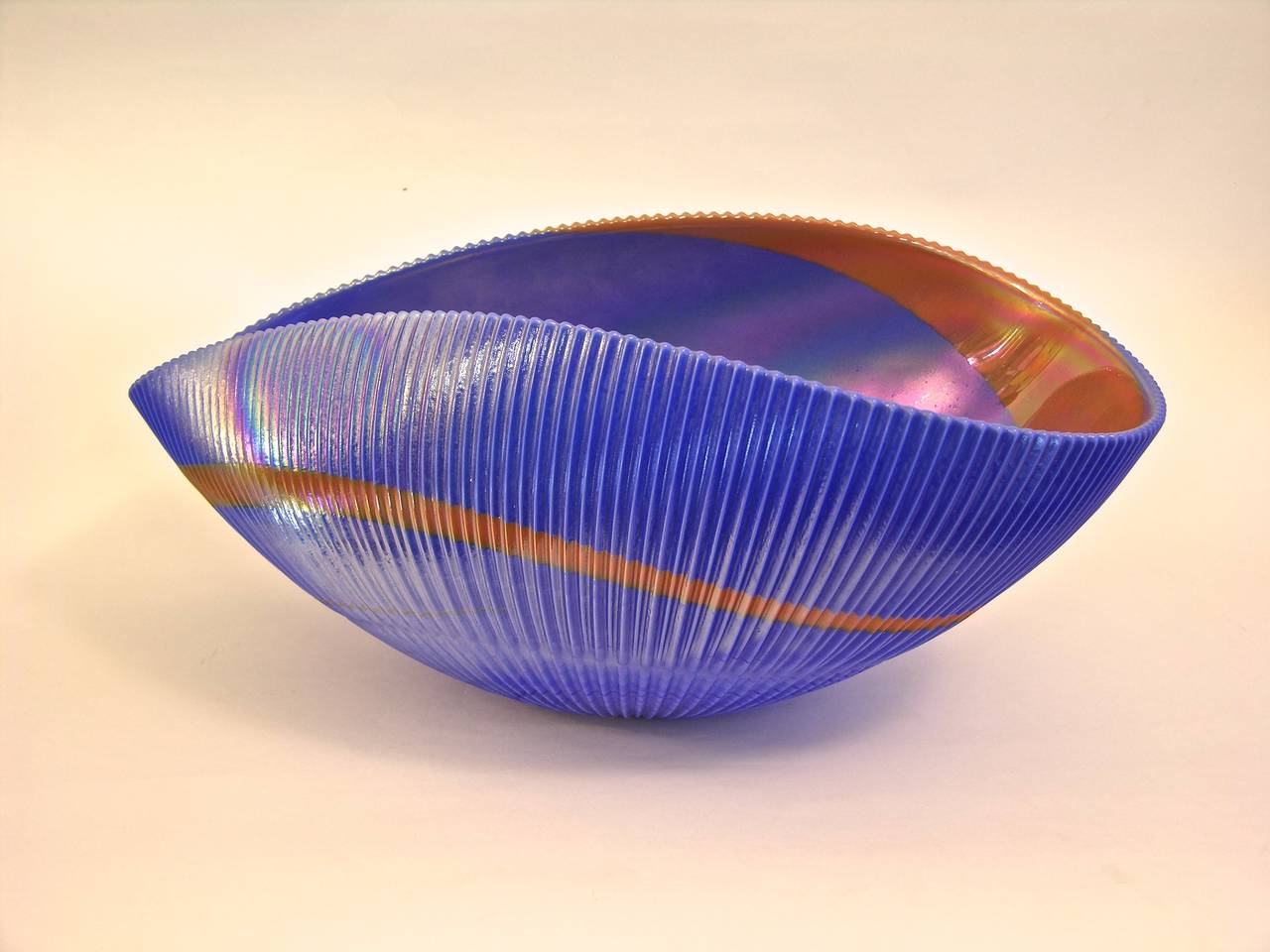 Venetian blown Murano glass center bowl from the 1990s by Ferro Murano, with an unusual folded almond shape and waved edge. The outside is skillfully ribbed and the blue body is decorated with a band swirling in and out, worked with avventurina, a