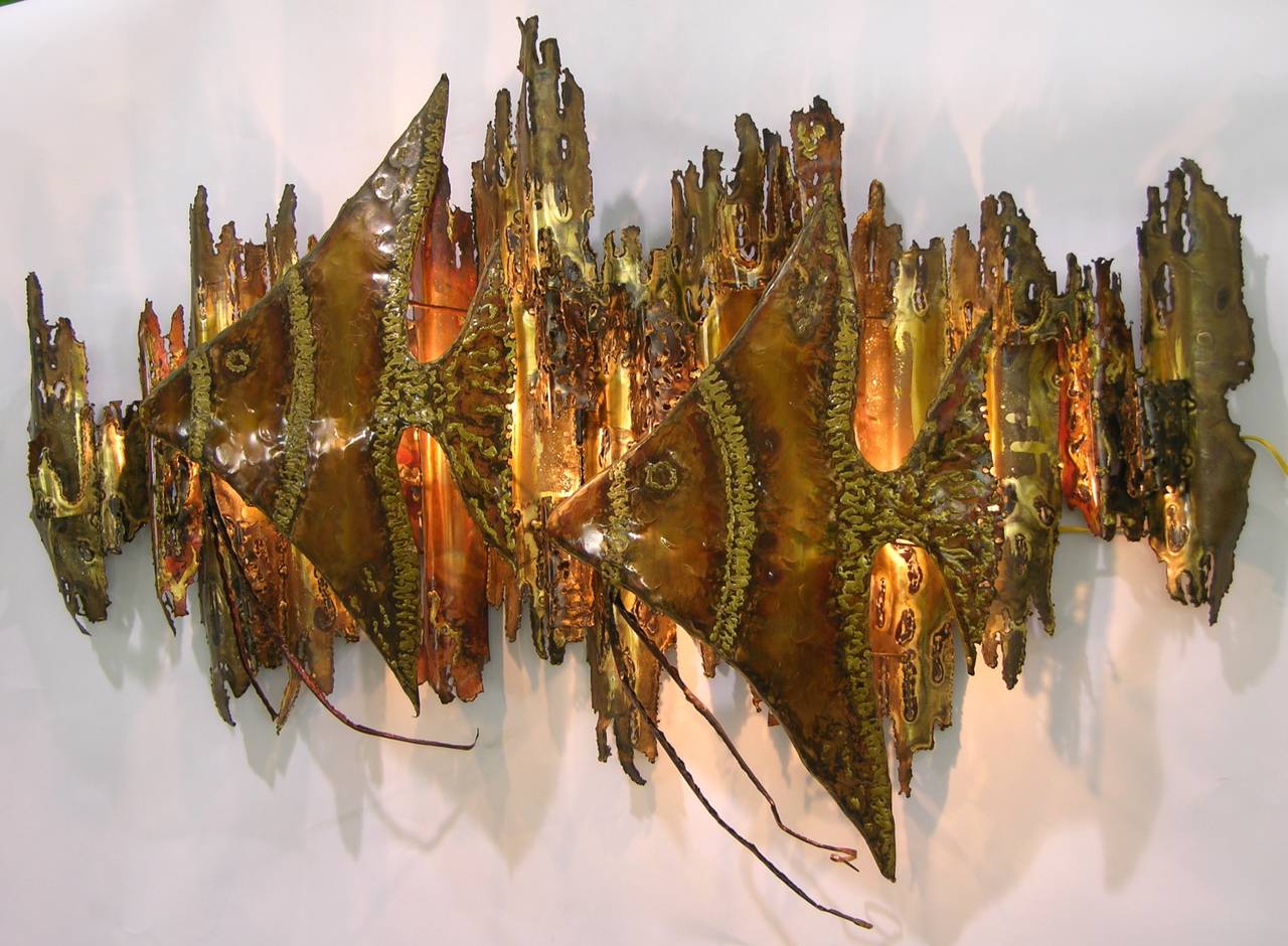 A very expressive Brutalist sculpture by Maine artist Ernie Abdelnour, in handcrafted copper and hand worked with a blowtorch, the two fishes floating off the waved background hide ingeniously the light sources that create shadows and an atmospheric
