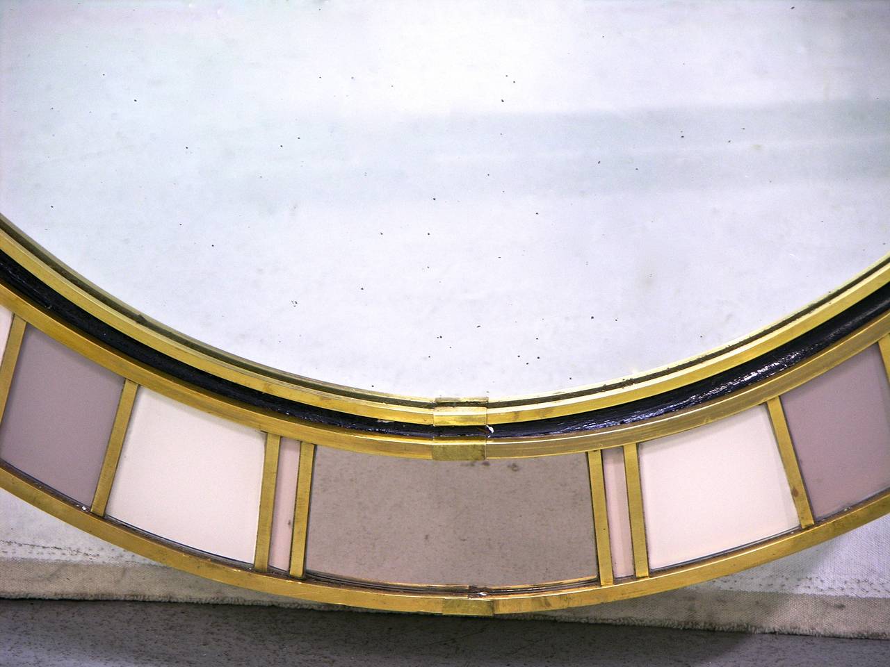 A custom-made unique sophisticated mirror, entirely handmade: The bronze edged central oval plate is framed by a concave black lacquered wood border that defines the substantial glass frame decorated with bronze insets that divide Murano glass and