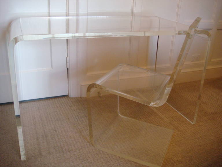 1970s, A stunning Modern Design desk and chair, both formed out of one continuous lucite piece with one inch thickness. The waterfall desk has sides that gracefully descend to the ground. The bent chair provides striking visual interest while