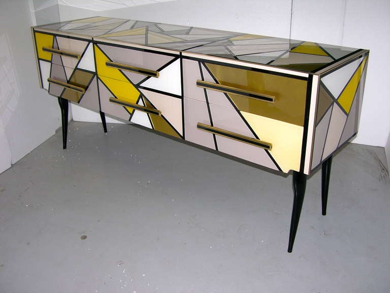 A very fun one of a kind 1970s Italian console/chest with a very enticing geometric design, unusual and rare colors for the surround all in glass, 6 drawers with hand made bronze handles highlighted with black glass, unique attention to details like
