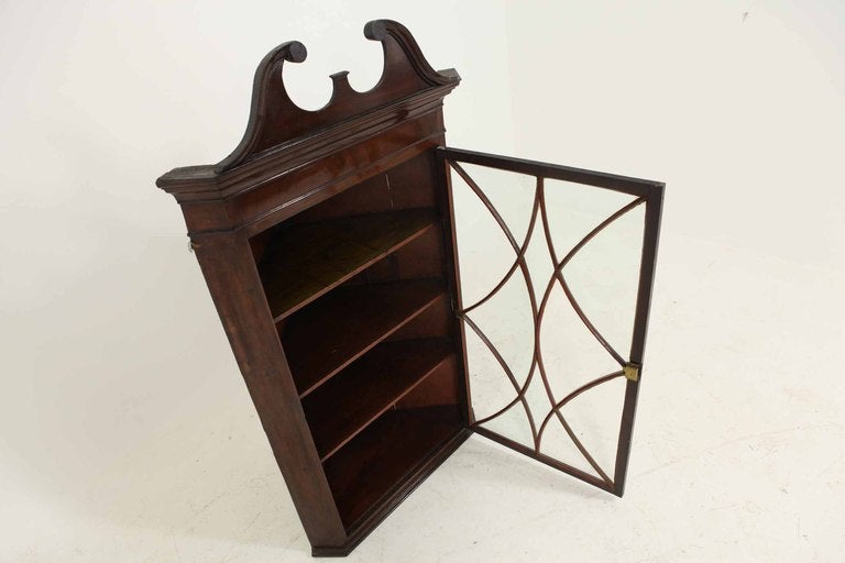 Mahogany glass fronted hanging corner cabinet, the swan neck pediment with dental cornice, beaded frieze, astragal glass door enclosing shelves, flanked by canted corners.

Shipping will be $185 by Greyhound.
