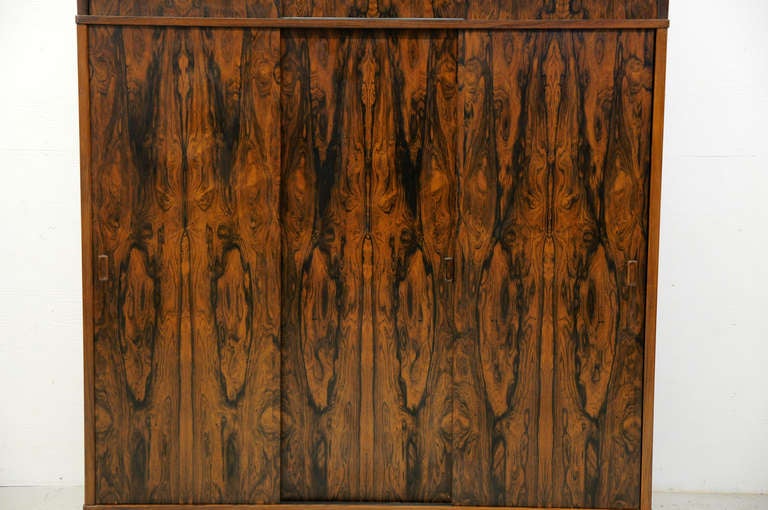 Stunning three door rosewood wardrobe, dating to the 60′s. A very high quality wardrobe with great style. The doors open nicely and its very clean inside. Three sliding doors above opens to a single shelf on either side. Below three sliding doors