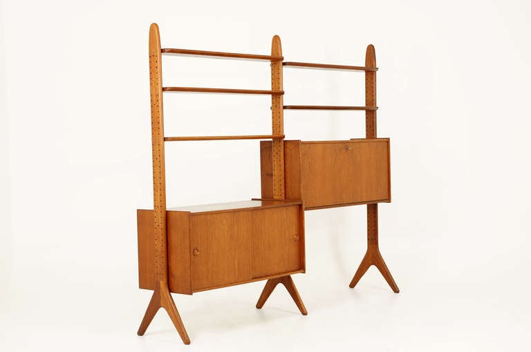 Stunning solid teak, free standing shelving unit or room divider designed in the late 50′s by Arne Hovmand-Olsen. Solid teak uprights support five solid teak shelves and two large cabinets. One cabinet has a drop down door and could be used as a