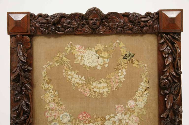 Beautiful, richly carved fire screen standing on carved shaped legs, the side supports being heavily carved.  The square top having decorative carvings, the needlepoint panel depicting a garland of flowers.

Shipping will be $145.00 by Greyhound.
