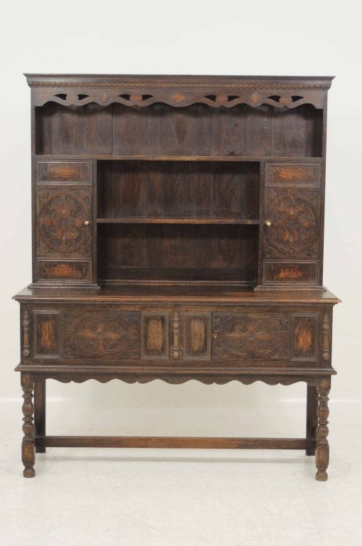 17th century oak Welsh dresser, the projected moulded cornice over pierced shaped apron, open shelves flanked by panelled doors, moulded rectangular top, matching panelled doors raised on balluster turned legs united by stretchers.