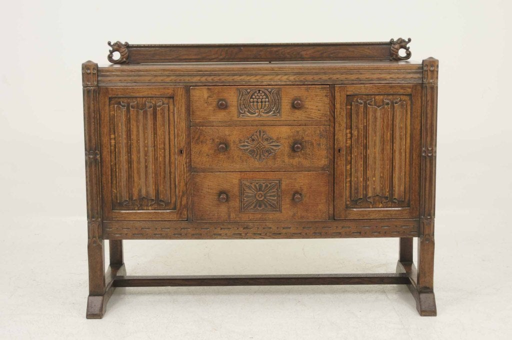 Oak sideboard with carved splash back over moulded rectangular top, over two (2) drawers flanked by linen fold doors raised on very thick legs united by cross stretcher.