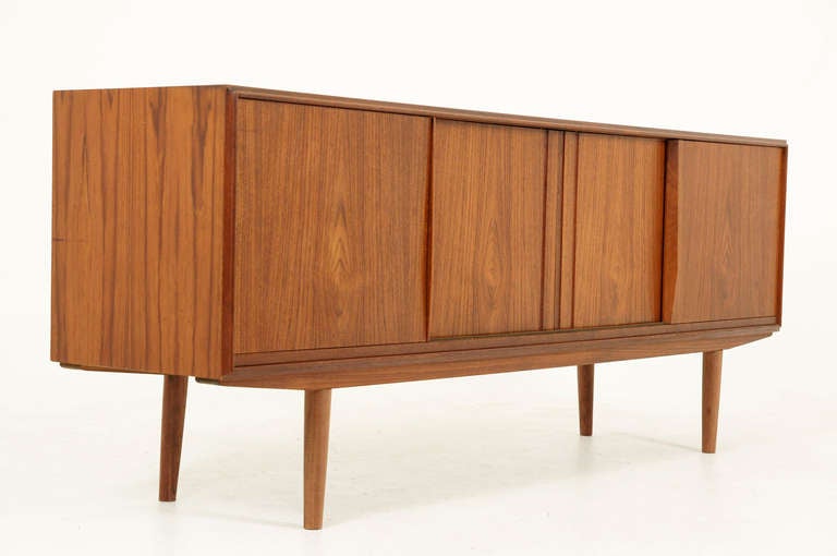 Nice Danish teak low sideboard dating to the 60's. Sideboard shows four sliding doors, which open to shelving and two small drawers, on the right and one adjustable shelf inside the left door. The two middle doors open to two adjustable shelves.