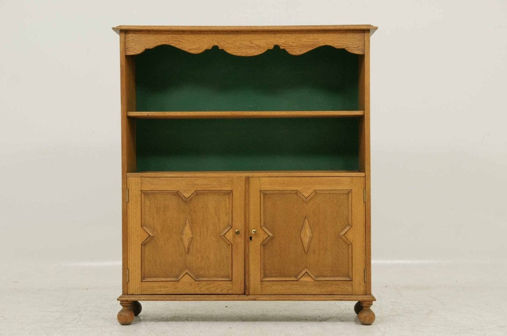 Early 20th century oak open bookcase with shaped frieze above open shelf, pair of panelled cupboard doors ending on bun feet.  Shipping will be $185.00 by Greyhound.