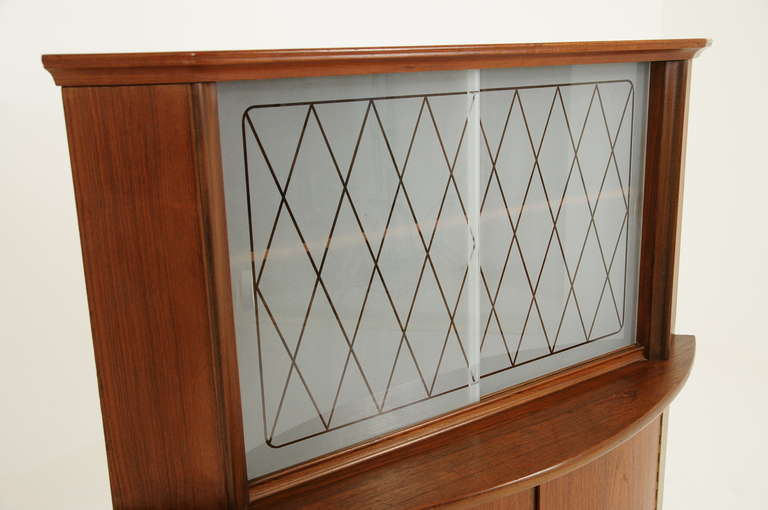 Lovely teak, Danish modern curved or bow front corner cabinet. Cabinet is a classic Danish teak design and has unique glass sliding doors. Curved doors below open to small shelves lined with felt. Large shelves above and below are removable.