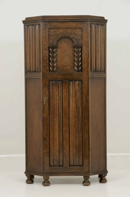 Early 20th century oak armoire with carved frieze above an arched carved barley twist door ending on bun feet.