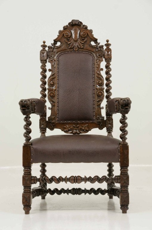 Ornately carved oak barley twist throine chair with carved and upholstered back and upholstered seat with lions head terminals, raised on block barley twist legs united by stretchers.