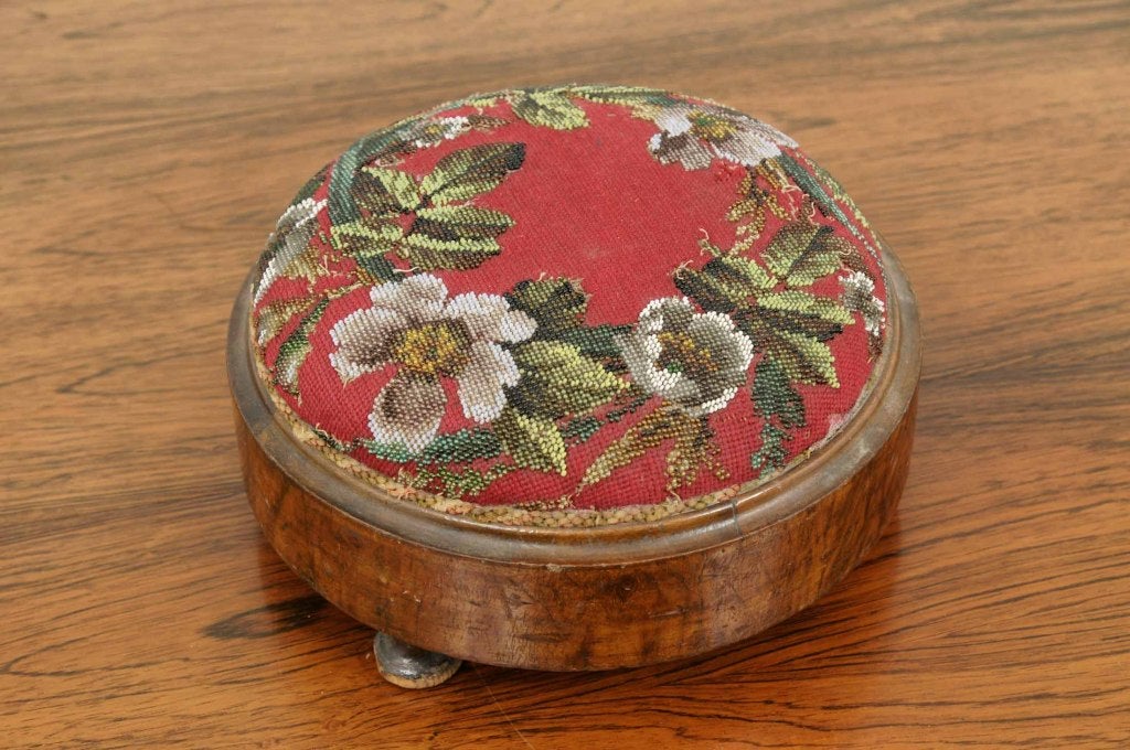 Petite Victorian circular footstool with beaded needlepoint top ending on bun feet.