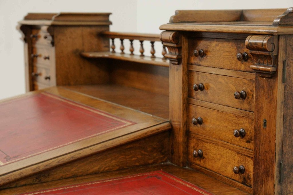 Magnificent Victorian oak Dickens desk with central galleried shelf, flanked by eight (8) small drawers above the slope, tooled leather top and flanked by nine (9) drawers on a plinth base.