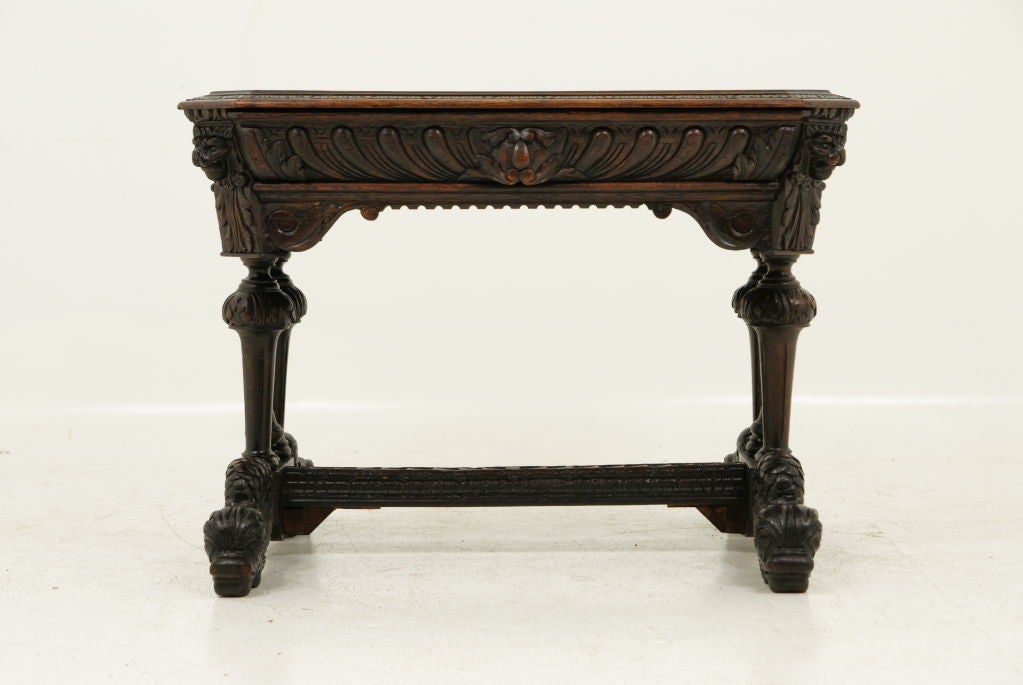 Solid carved oak library table in original condition with detailed carving on all sides, carved lions masks, canted corners, carved arches sitting on a heavily carved dolphin base.<br />
<br />
************** Important Customs Information