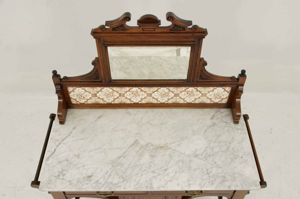 Victorian mahogany marble top washstand with bevelled mirror above, backsplash with tiles, over a white marble, with two (2) towel rails to the sides, two (2) drawers above a single door cupboard ending on castors.
