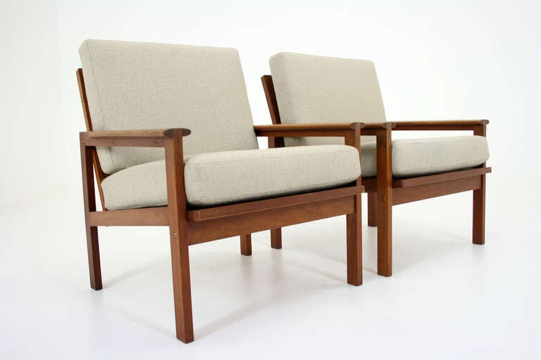 Beautiful pair of teak easy chairs by Illum Wikkelso for N. Eilersen. The unique joint of the arms are a nice touch to the otherwise simple and minimalist form and are highlight of the design. Chairs have just been reupholstered in a beautiful light
