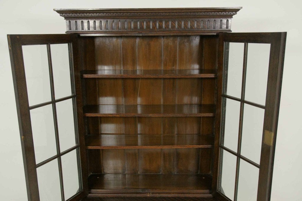 Very tall solid oak barley twist cabinet bookcase with ornately carved cornice above a pair of astragal doors, enclosed three (3) adjustable shelves above two (2) panelled cupboard doors ending on barley twist supports with stretcher base.