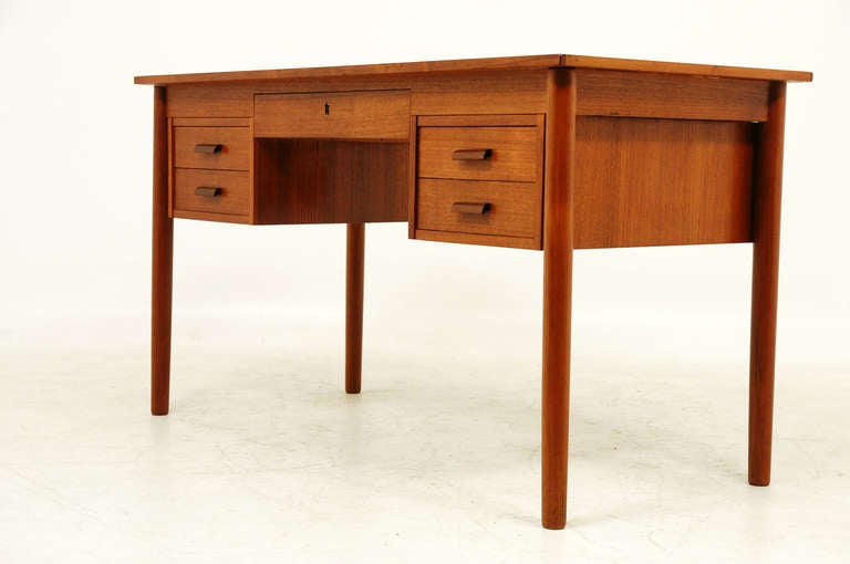 Simple Danish, teak flat top writing desk. Central drawer above knee hole and two drawers down each side add plenty of  function. Back side has a finish back. Top shows minor marks consistent with age but does not detract. Condition is very good and