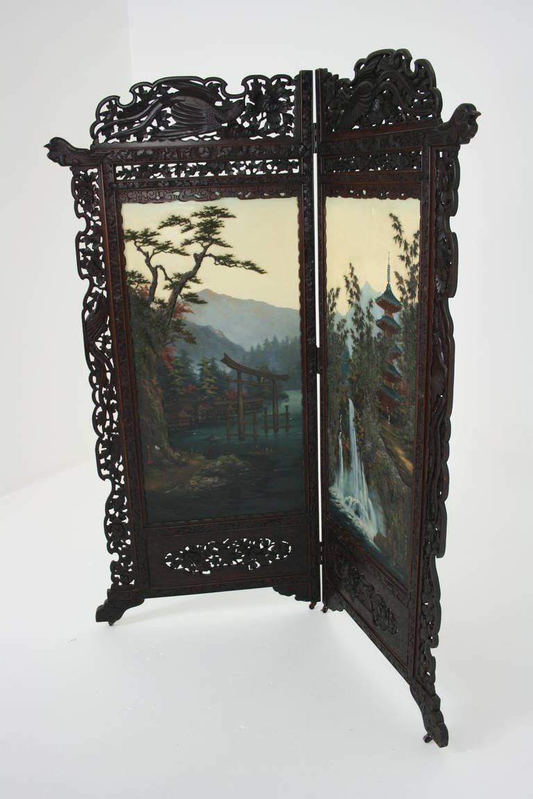 Japan, 19th century. Two-panel floor screen, heavily carved and pierced frame. Two landscape design panels, finished, lacquered back. Original castors. 58