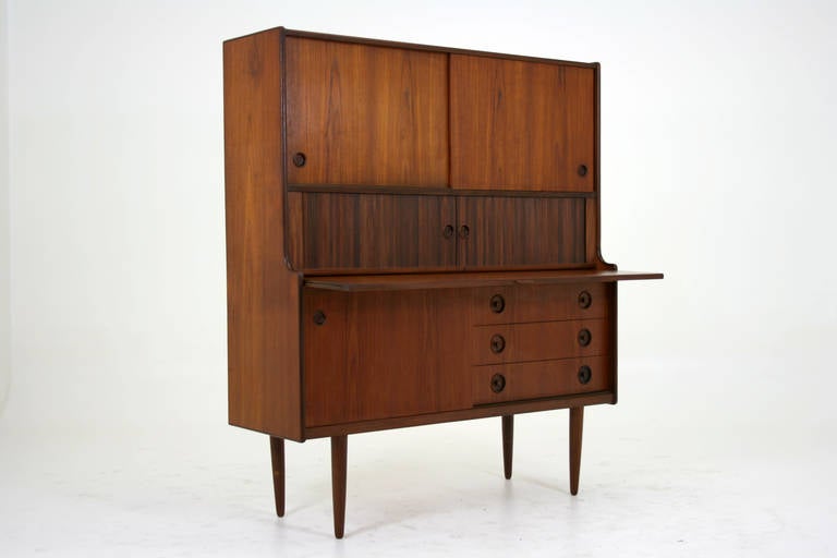 Teak sideboard cabinet with slide out bar counter and drawer storage. A great design that has so many storage features and application options. Three large sliding doors, three drawers below, sliding tambour doors and a pull out bar counter surface