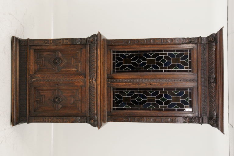 Victorian carved oak bookcase with two upper doors with original stain glass over center drawer and below two carved panel doors with carved lions heads and busts.  Dark oak finish.<br />
<br />
************** Important Customs Information
