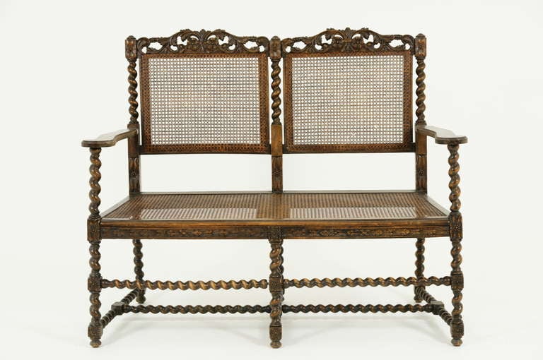 A late 19th Century Walnut Barley Twist Sofa, Settee or Hall Bench with carved top rail, caned back with barley twist uprights above caned seat ending on barley twist legs joined by cross stretchers.