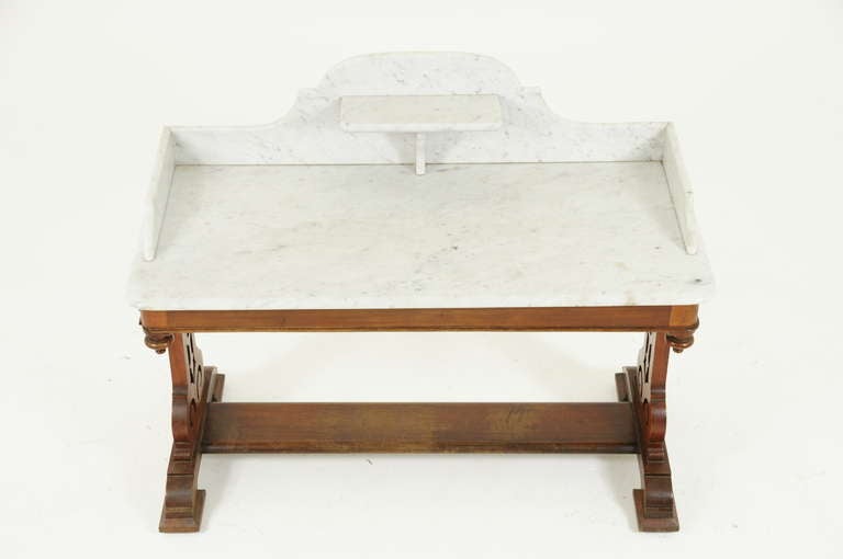 A very clean Victorian Mahogany Marble-Top Washstand constructed from quality mahogany.  It has a Carreras marble top with shaped backsplash and small shelf to the center, shaped sides, standing on lyre-end supports with a central platform ending on