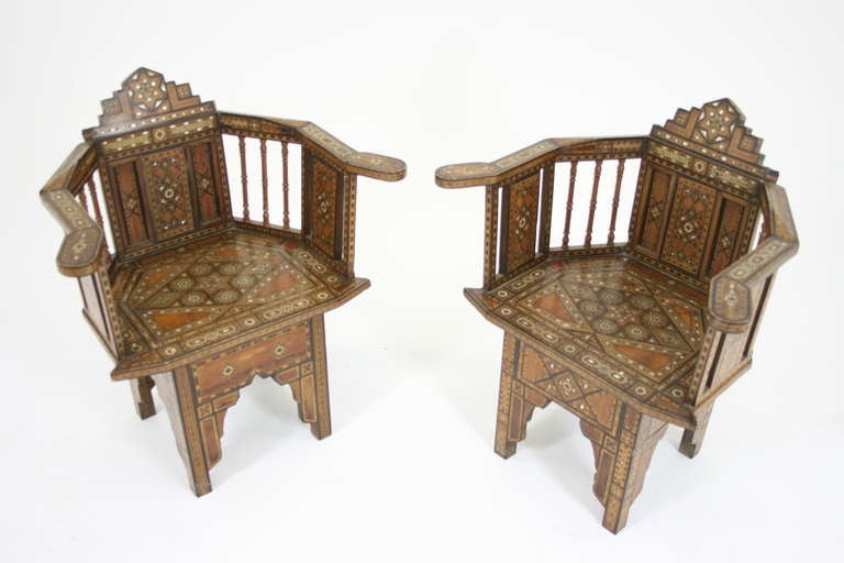 A pair of Syrian Inlaid Arm Chairs with horseshoe-shaped back and arms raised on spindles and panels inlaid with mother of pearl and bone star and mosaic motifs raised on arched supports.