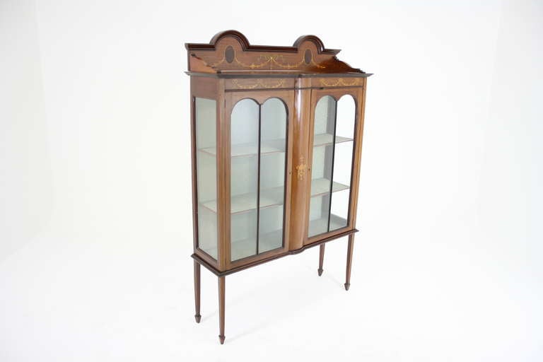 An antique Mahogany Inlaid China Display Cabinet with three-quarter gallery above two astragal doors revealing two lined wooden shelves, ending on a fine inlaid tapered legs.