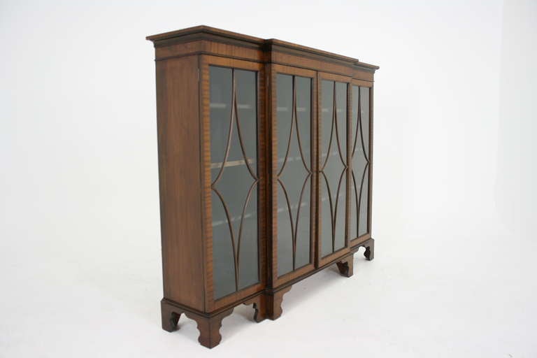 A good quality mahogany four-door breakfront bookcase, display cabinet, the moulded rectangular top over four astragal glass doors opening to reveal nine adjustable wooden shelves ending on bracket feet.