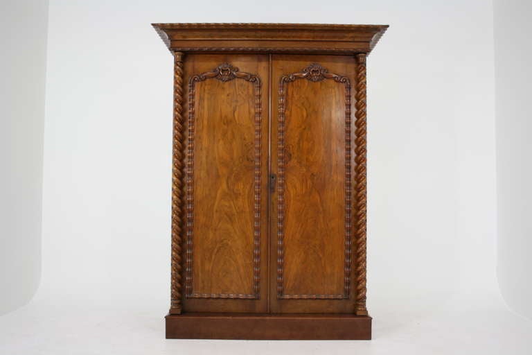 A Victorian Mahogany Double Door Armoire with cornice top, projecting frieze above two carved doors and large barley twist columns on either side.  Internally there is full hanging space on the left side, fine graduating drawers on the right side,