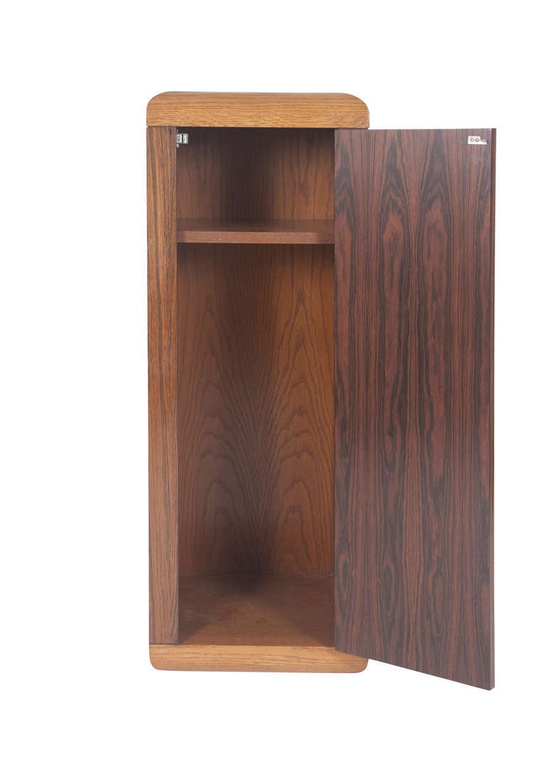 Dunbar rosewood pedestal with concealed storage, 1974. Oak trim to top, one spring-loaded door with concealed hinge, dated two shelves to interior, original finish, signed with Dunbar paper showroom sample label. Measures: 15