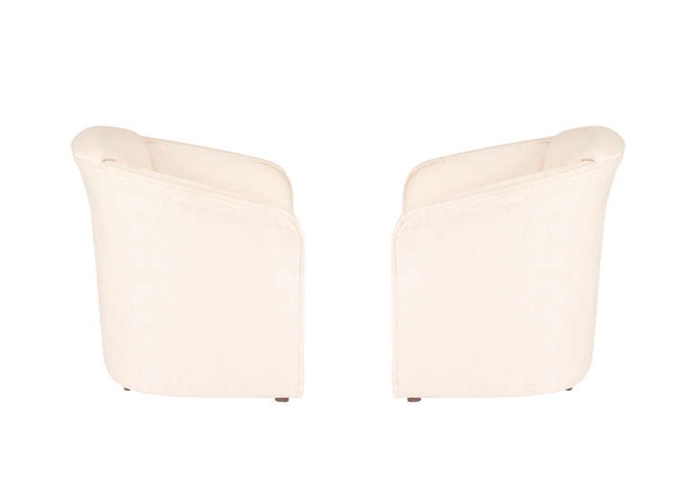 Pair of Club Chairs in the style of Karl Springer. Barrel Back with detailed welting on arms. In cream, striated (lightly-patterned) upholstery.