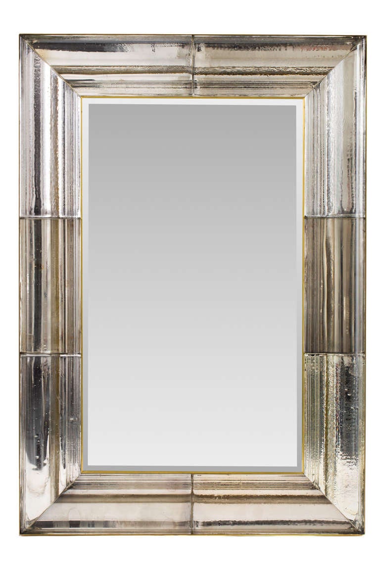 Exquisite large scale mirror composed of eight individually hand cast mirrored glass moldings insterted within a solid brass frame. Inner brass detail surrounding beveled mirror. Weight approximately 200 lbs. One of a kind.