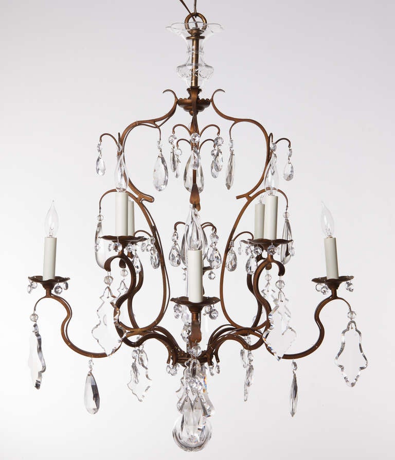 Neoclassical crystal obelisk chandelier has eight lights and faceted hand cut crystals of varying shapes and sizes hang on a patinated wrought iron frame. 