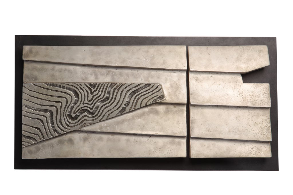 Abstract hand cast aluminum wall sculpture mounted on wood board frame.
 Signed and dated, 1981.