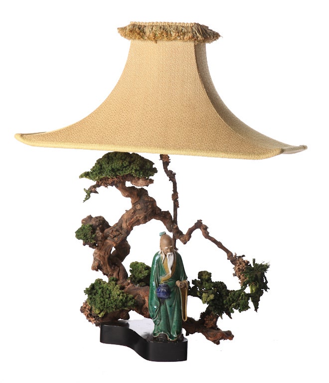 Asian figural lamp after Billy Haines, surrounded by faux bonsai tree on ebonized base. Original pagoda lamp shade included, measures 24 inches W x 12.5 inches D.